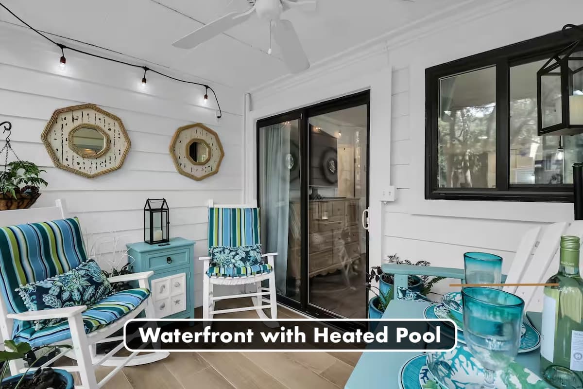 Bright screened-in porch with coastal decor, rocking chairs, and outdoor dining