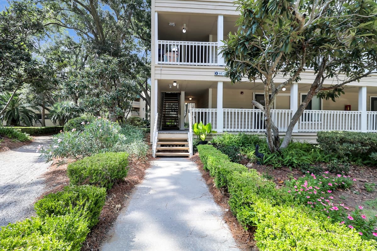Condo building exterior with lush landscaping and covered porches