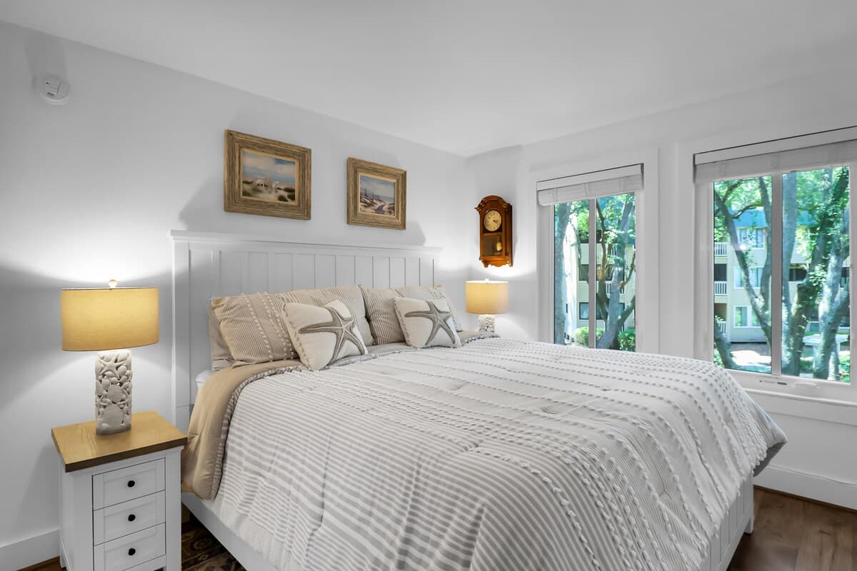 Master king suite with starfish pillows, coastal art, and garden views