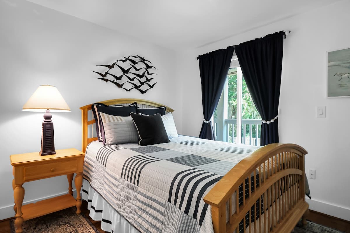 Guest queen bedroom with nautical bird art and balcony access