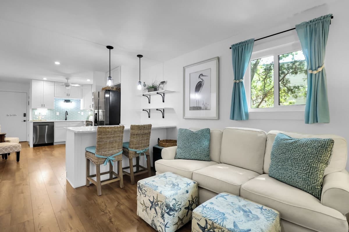 Spacious living room with 65-inch Roku TV, coastal sofa, and kitchen view