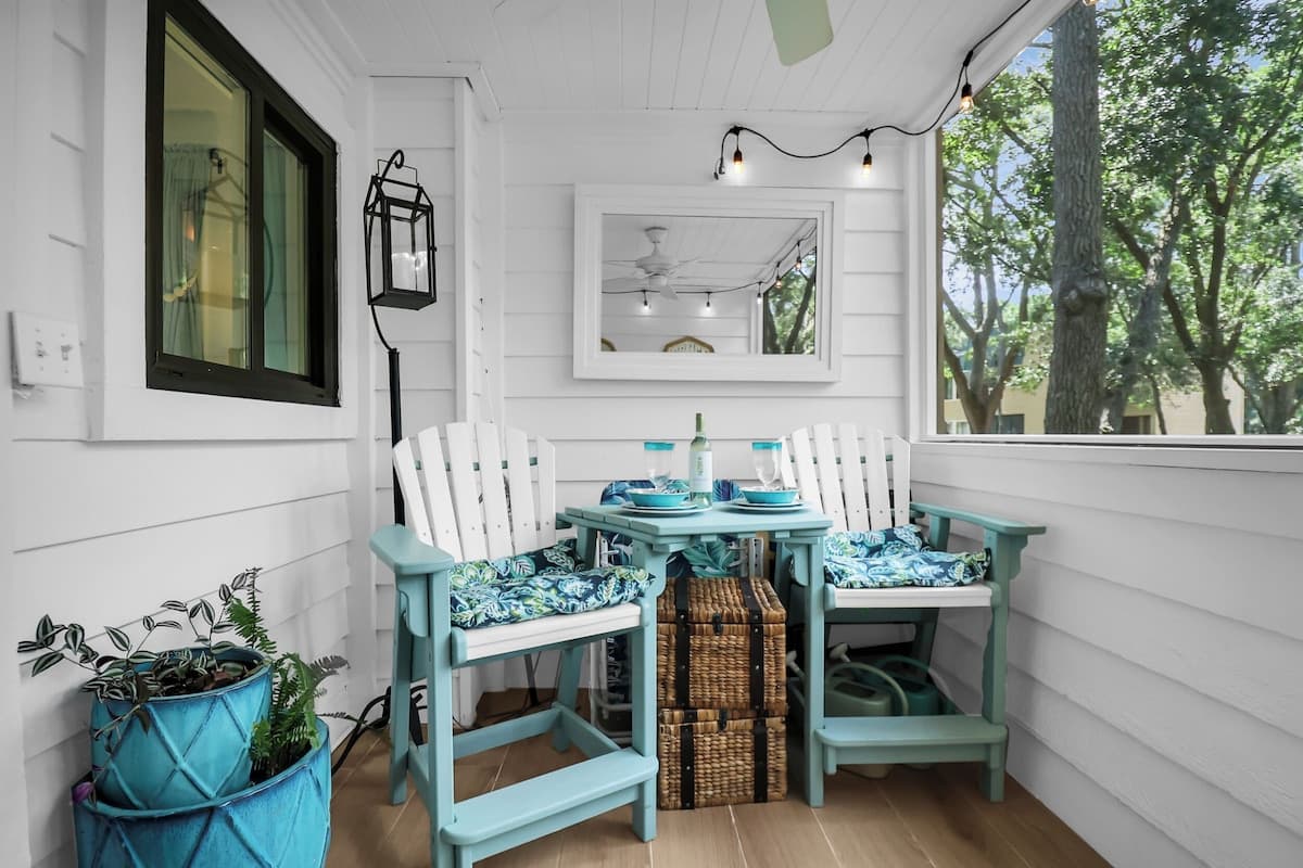 Cozy screened porch with rocking chairs, string lights, and garden views