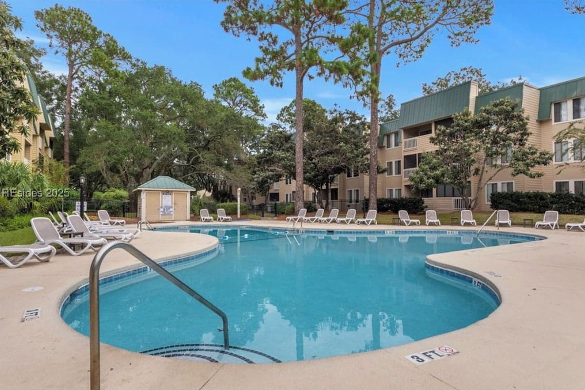 Resort outdoor pool surrounded by lounge chairs and live oaks